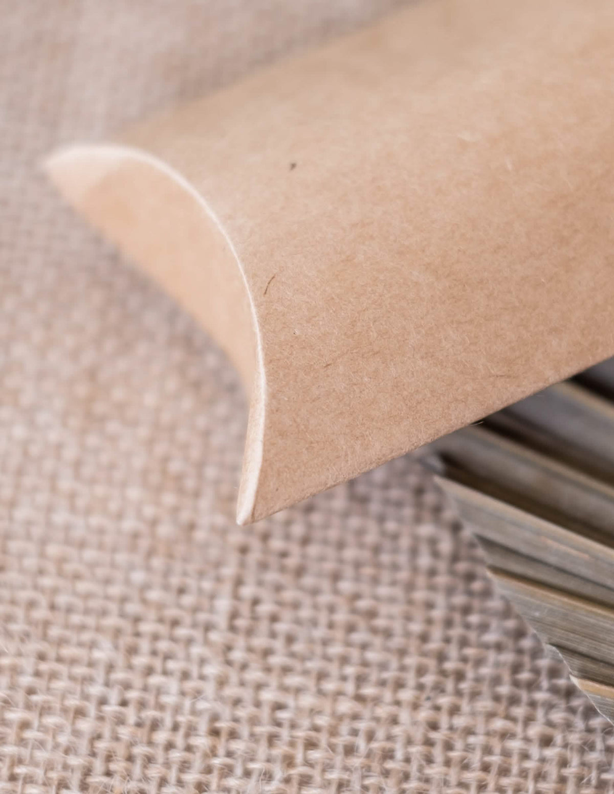 Detalhe do fecho curvo das pequenas caixas kraft para festa castanho claro em forma de berlingot