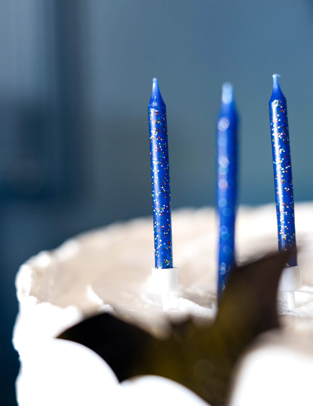 Zoom sobre o suporte e as purpurinas das 12 velas de aniversário para bolo azuis com purpurinas