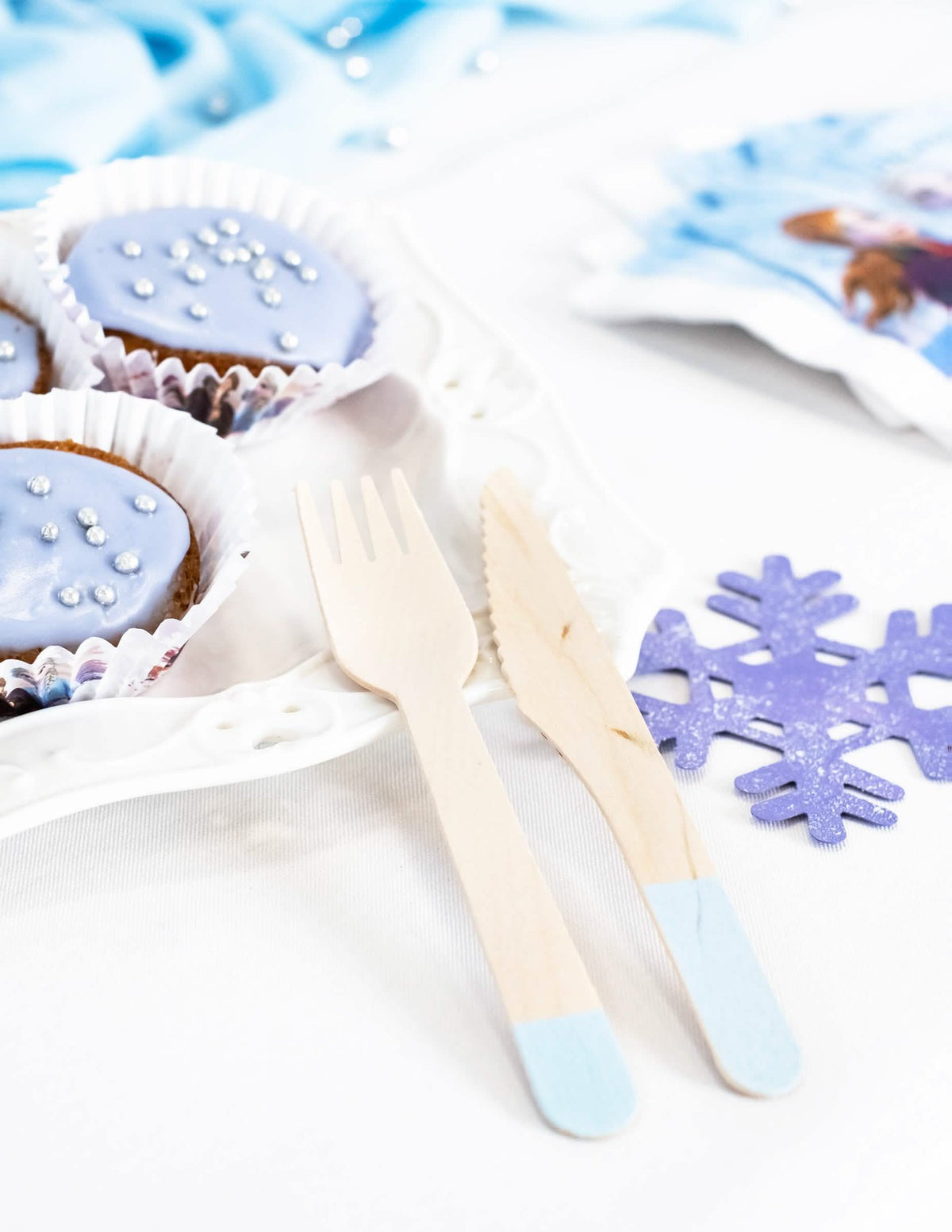 Mise em cena com cupcakes e floco de neve dos talheres em madeira para festa azul céu
