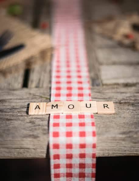 Palavra AMOUR numa decoração de mesa axadrezada de 60 letras de alfabeto ao estilo do Scrabble para decoração de mesa em madeira