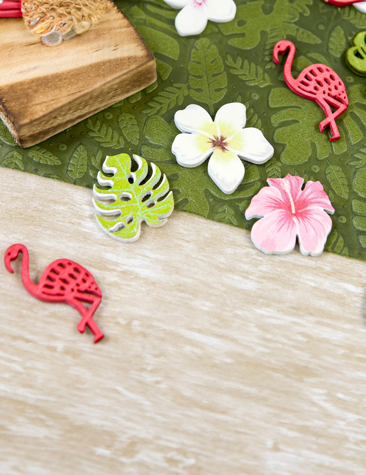 Mise em situação decorativa dos confettis em madeira flores e folhas tropicais