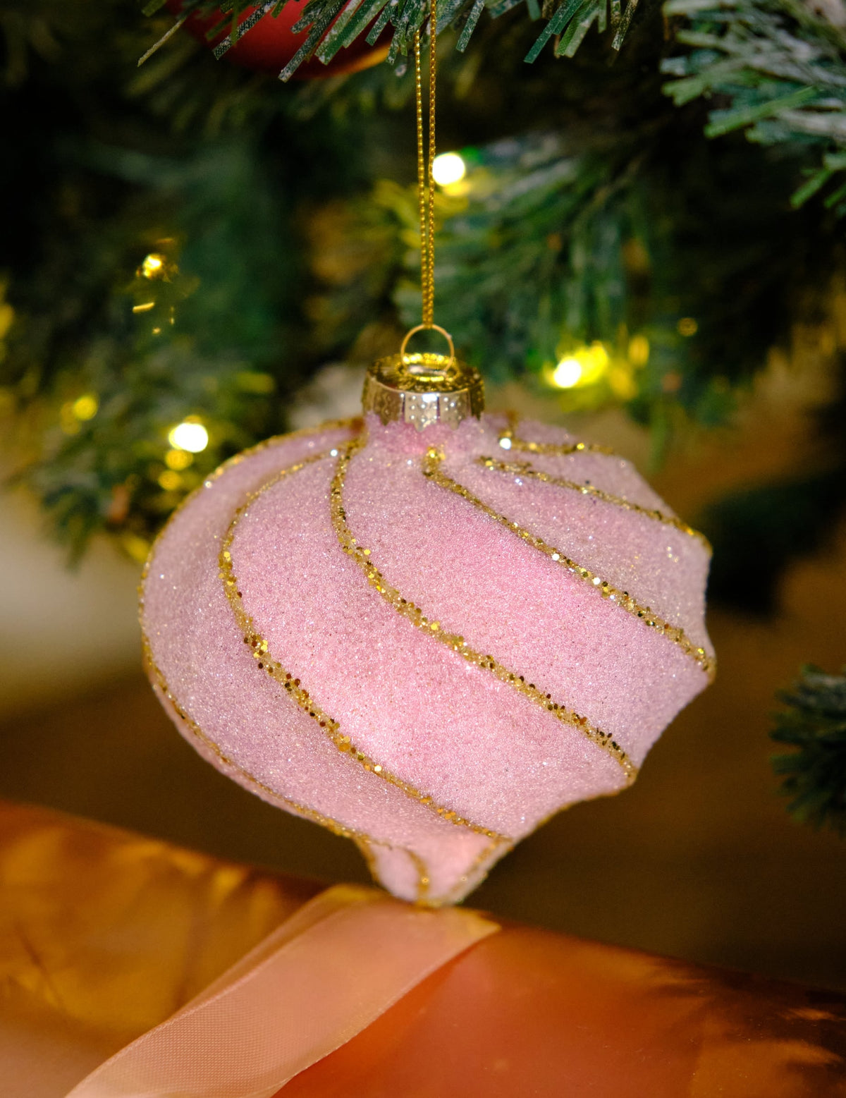 Gros plan sur la boule de noël forme goutte et spirales rose et or pailletée