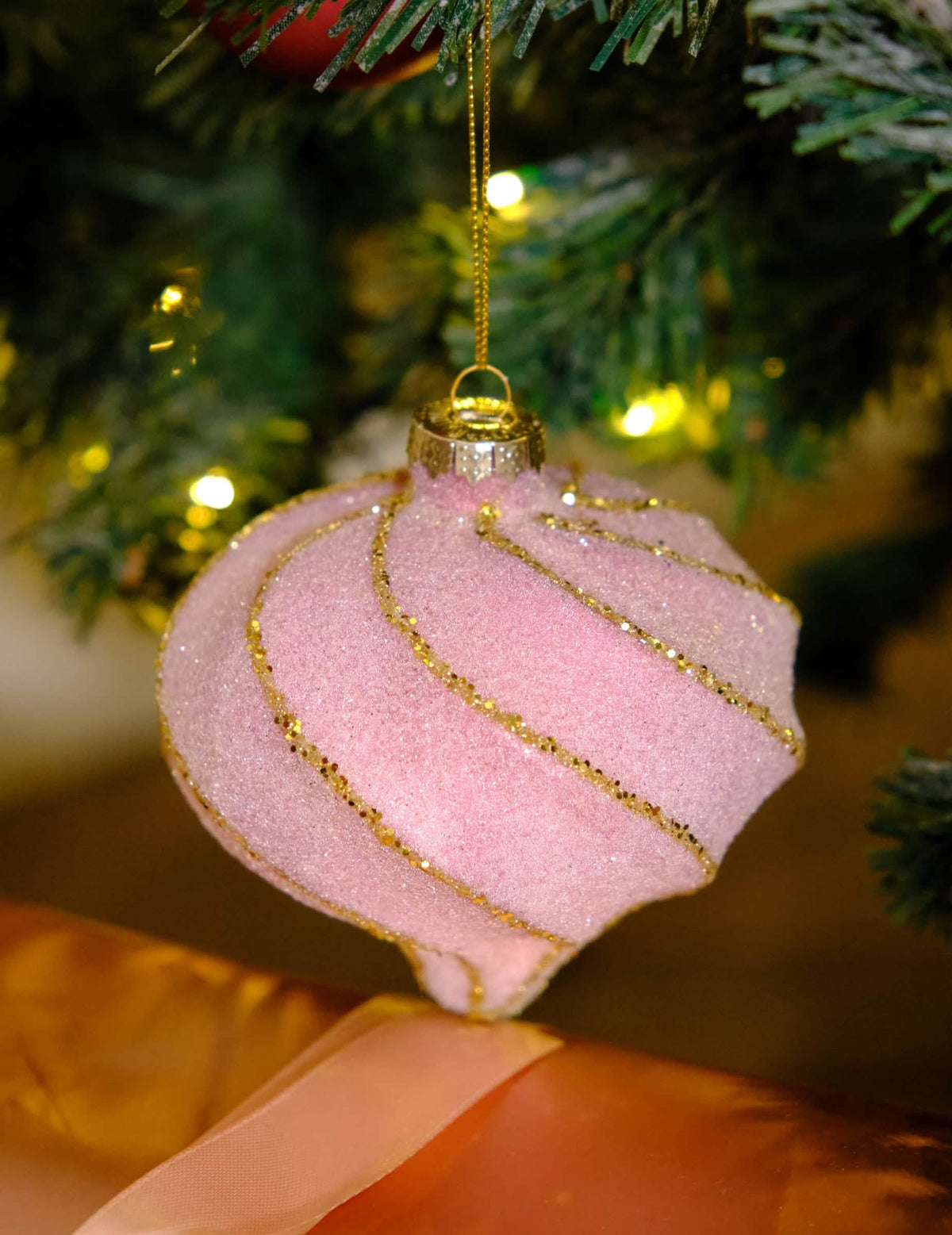 Grande plano da bola de natal em forma de gota e espirais cor de rosa e dourado com glitter