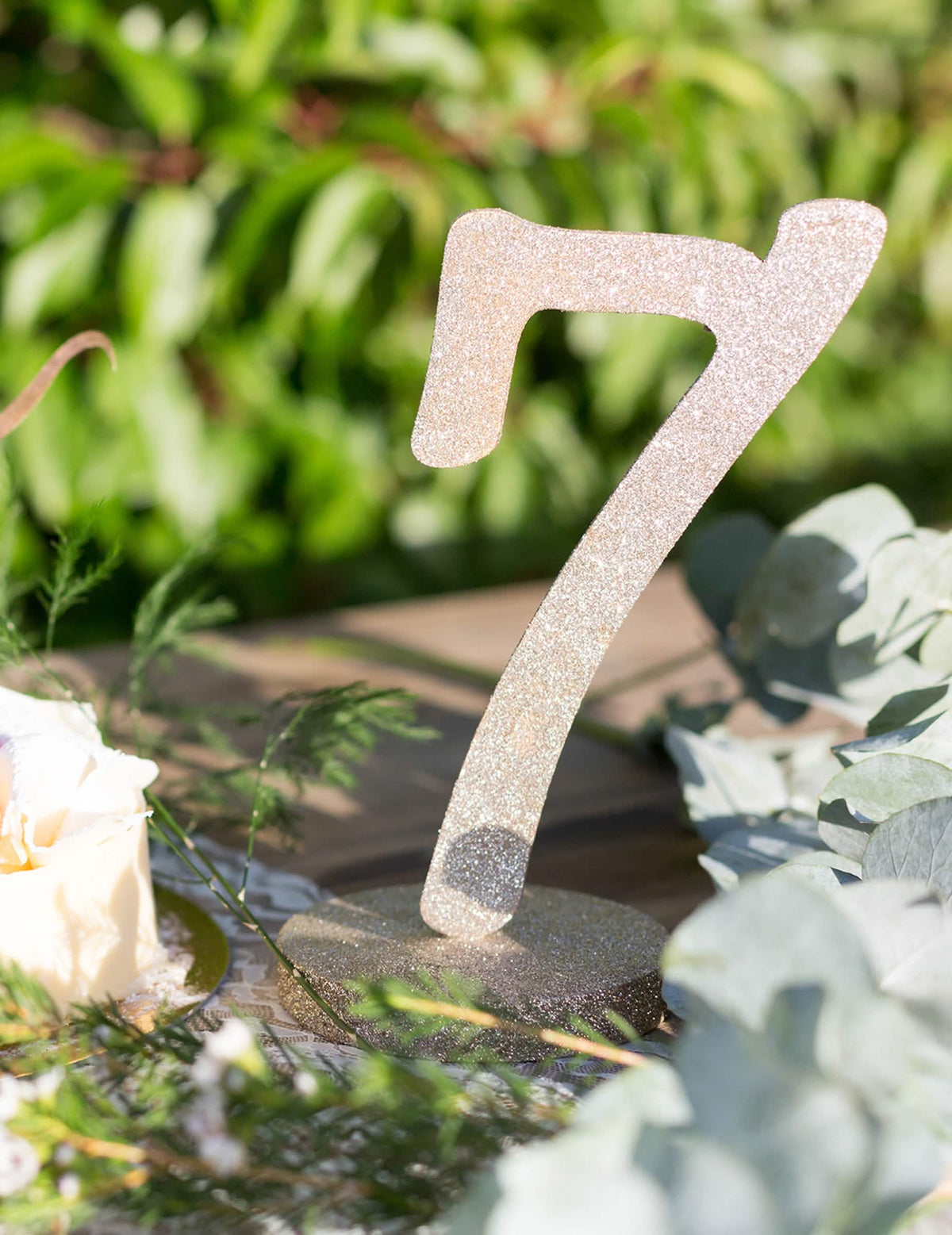 Grande plano do centro de mesa número 7 em madeira com purpurina champanhe sobre base