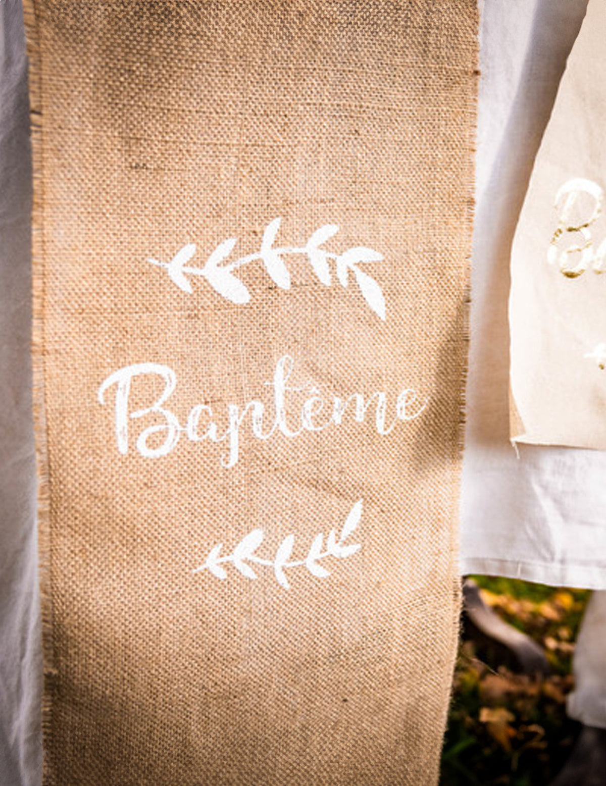 Detalhe da inscrição do caminho de mesa para baptizado e folhagens para festa