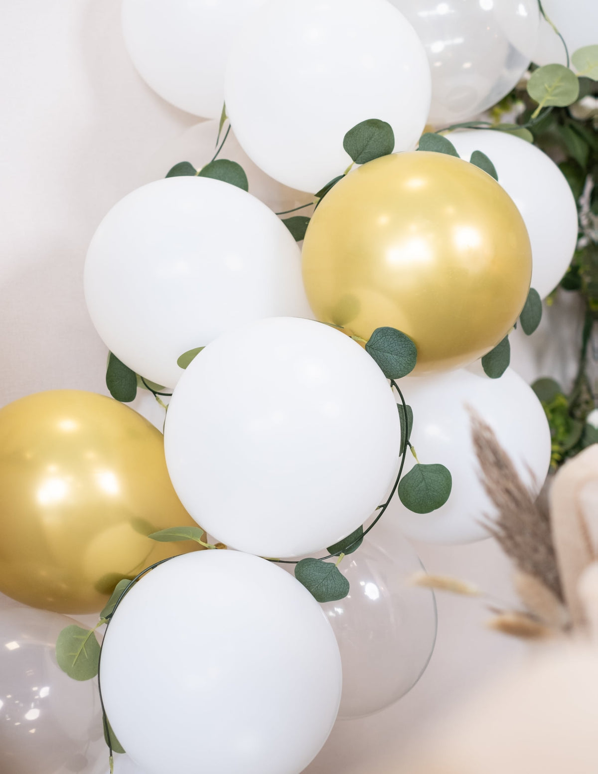 Grande plano sobre os balões e a folhagem do kit arco de 60 balões branco e dourado com eucalipto vegetal