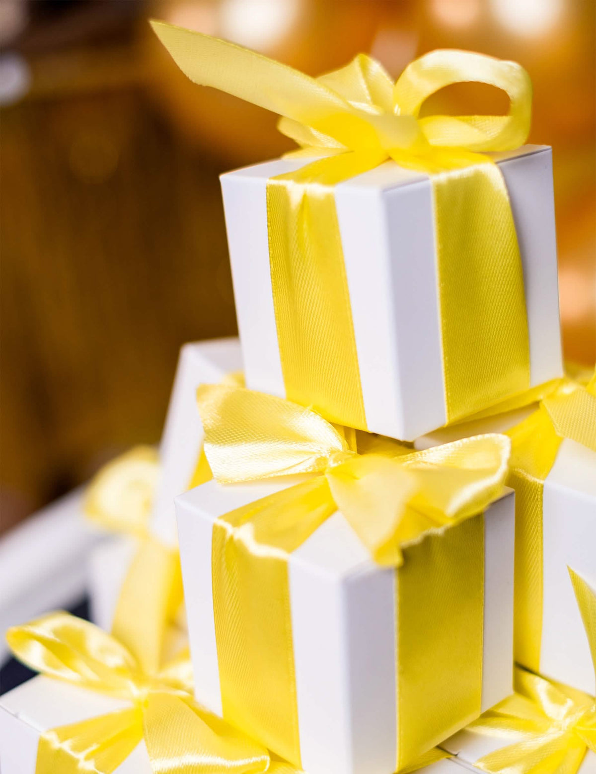 Empilhamento de caixas de presente decoradas com fita de cetim amarelo limão para decoração de festa
