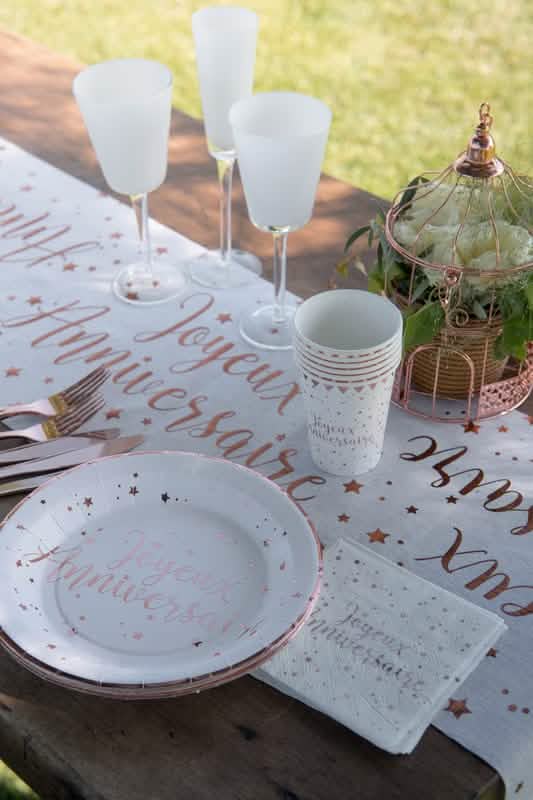 Montagem de mesa de festa com pratos de cartão brancos e ouro rosa com estrelas para aniversário
