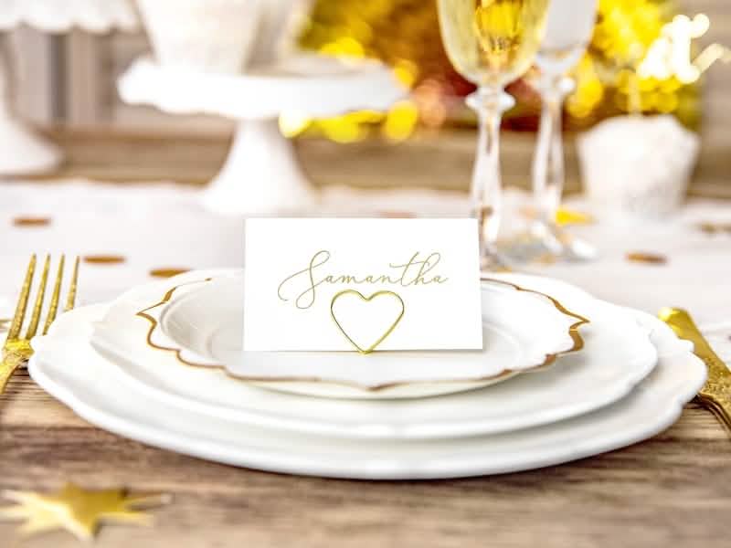 Mise em situação sobre uma mesa do marcador de lugar coração para casamento dourado