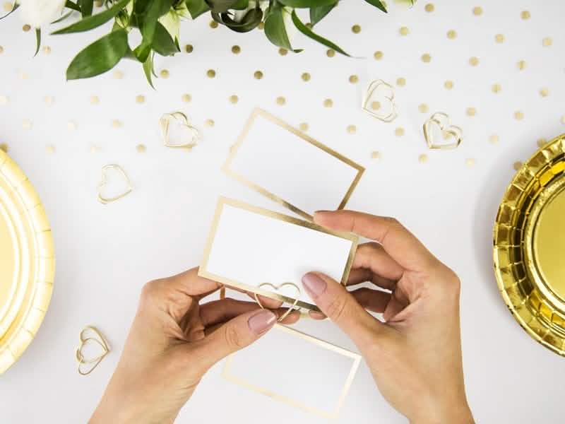 Detalhe da instalação do marcador de lugar em forma de coração para casamento dourado
