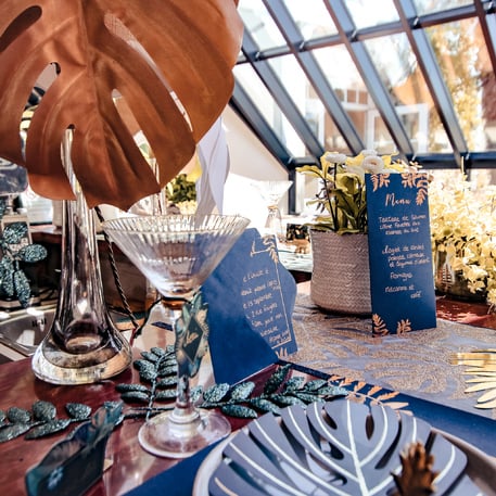 Mise en scène sur table de fête du menu fougères pour mariage bleu marine et cuivre