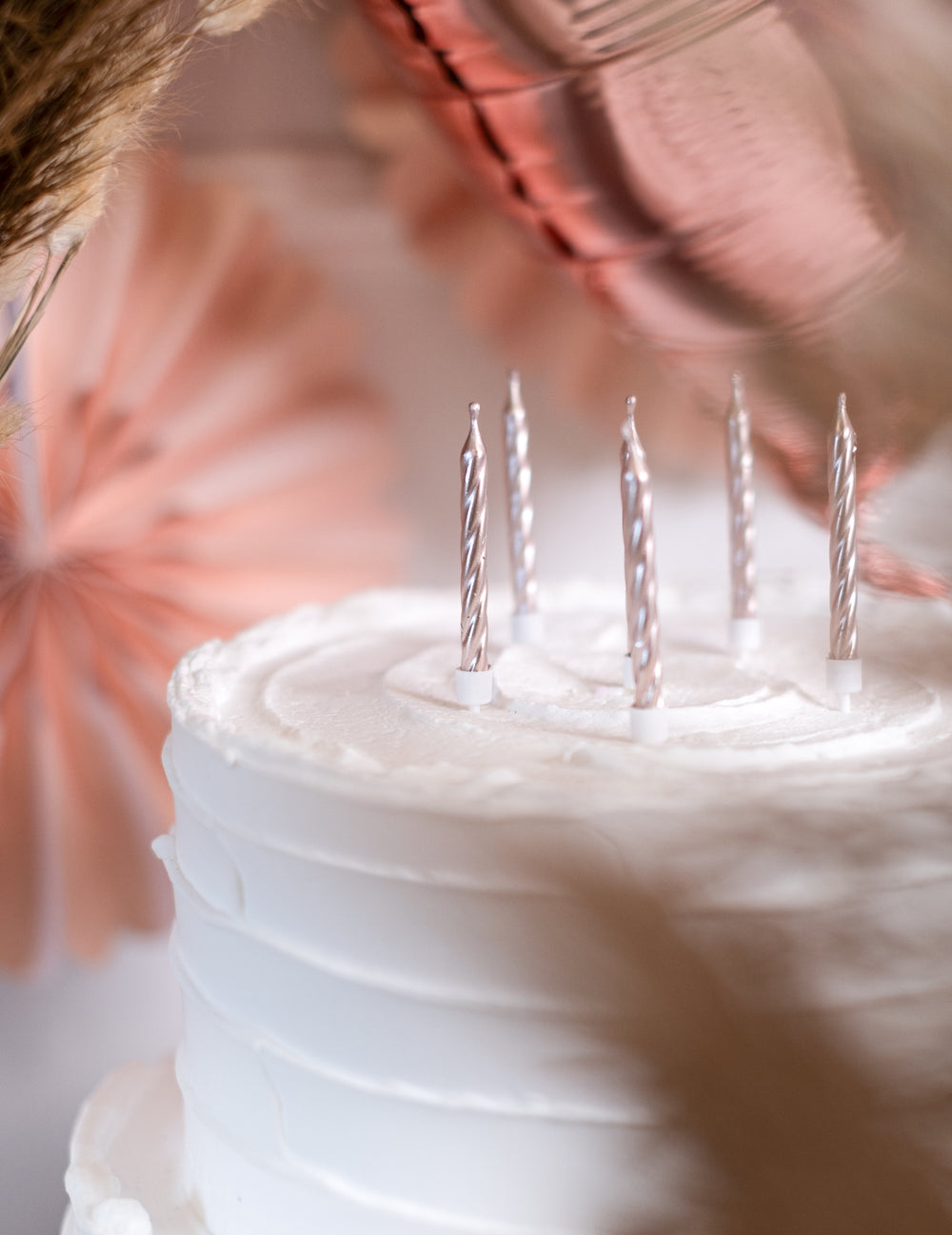 Gros plan des bougies sur un gâteau du 12 bougies d'anniversaire rose gold métallique avec supports