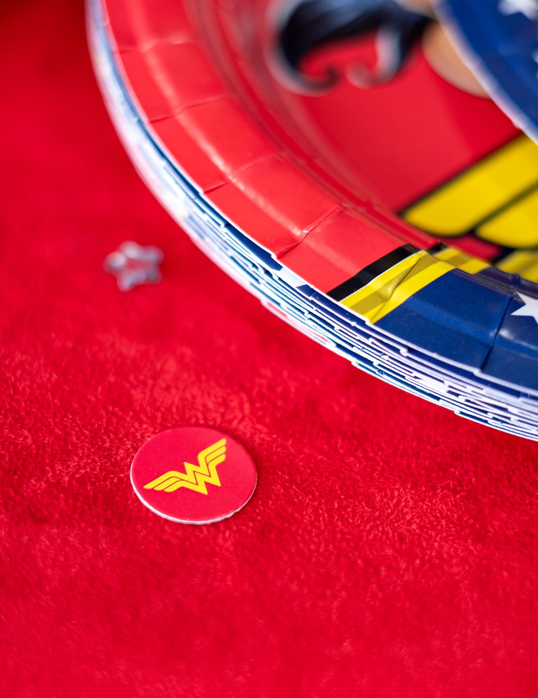 Détail d'un confetti à côté d'assiettes de fête du confettis Wonder Woman
