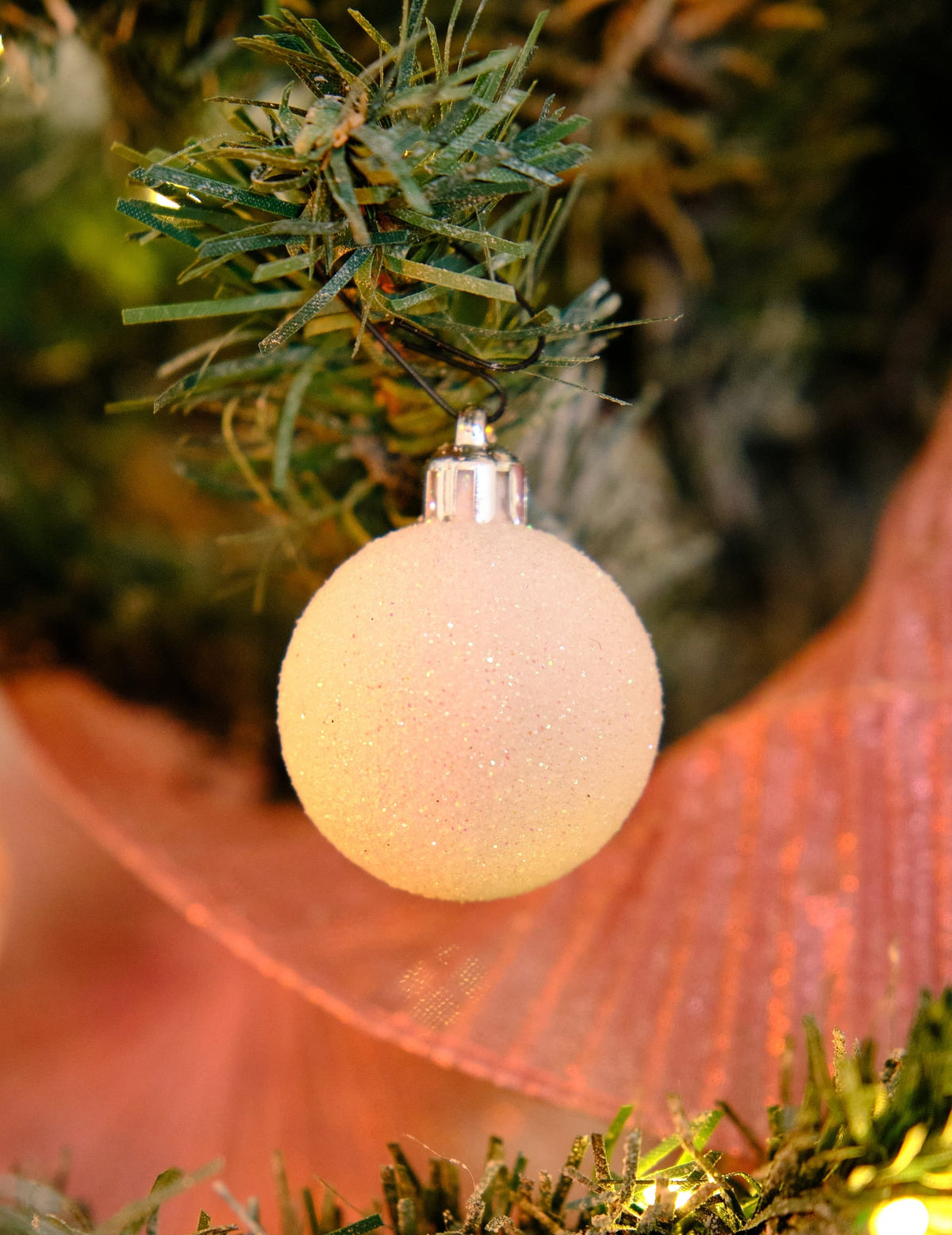 Gros plan d'une boule pailletée du lot de 18 mini boules de Noël blanches pailletées et mates