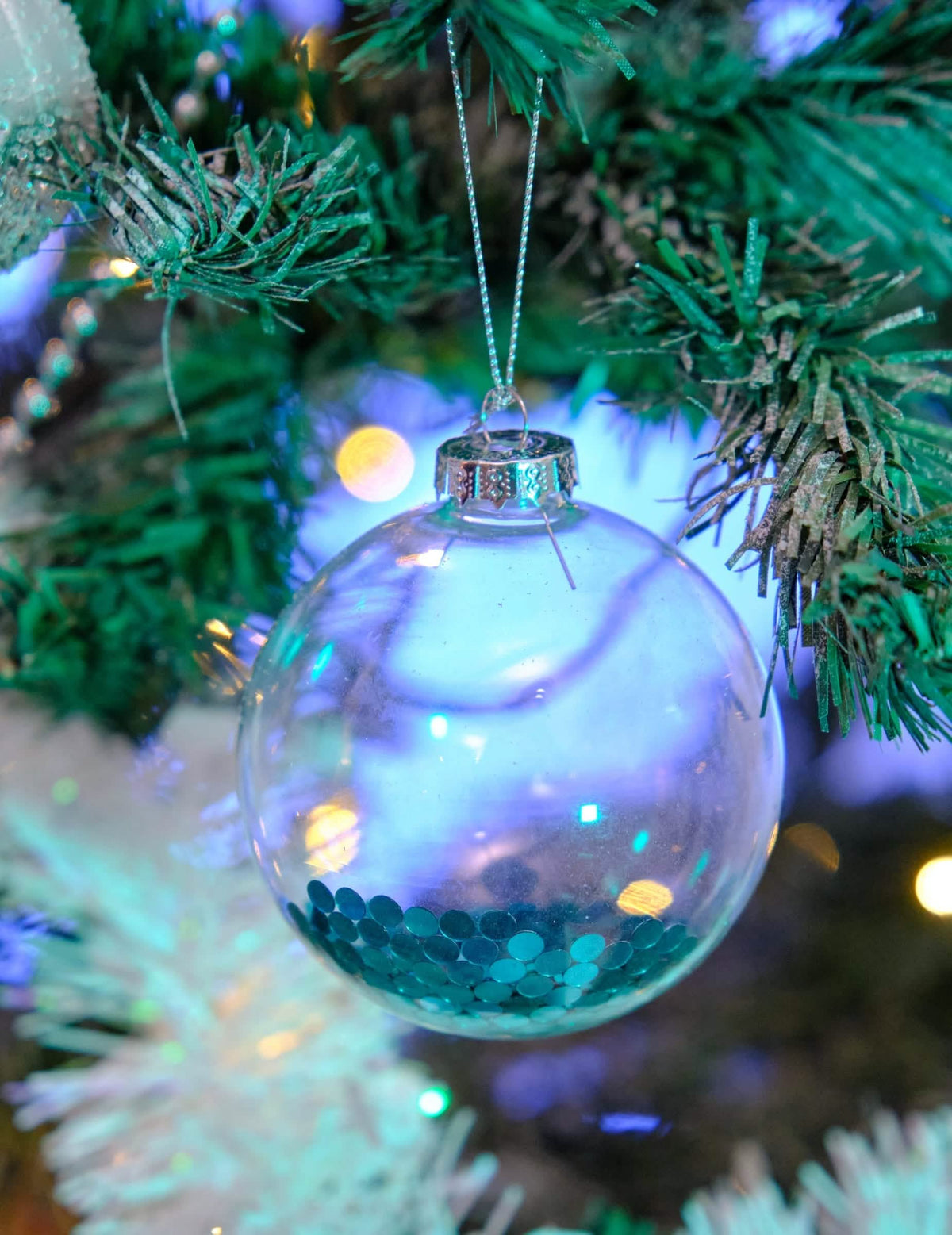 Vista aproximada das bolas de vidro de natal para árvore transparentes com purpurinas azuis