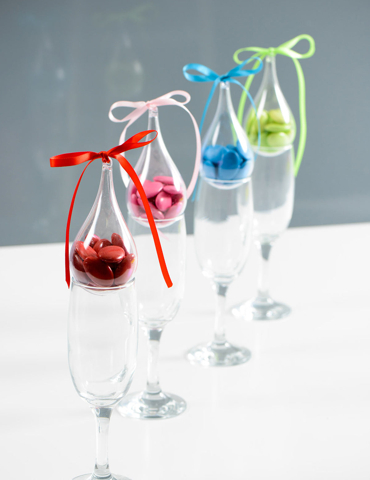 Mise en situation avec dragées colorées du contenant goutte d'eau à suspendre pour décoration de fête transparent