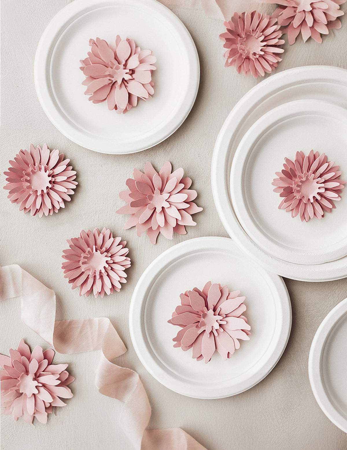 Mise en scène sur des assiettes des fleurs en papier 3D pour décoration rose poudré