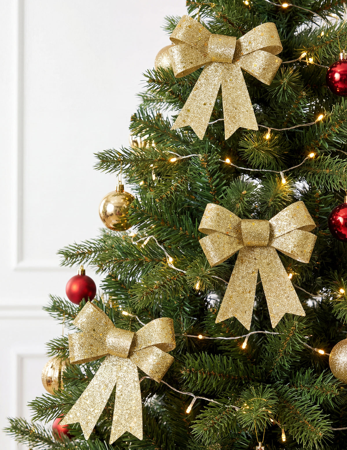 Mise en situation sur un sapin de Noël du lot de 3 nœuds à paillettes pour décoration dorés
