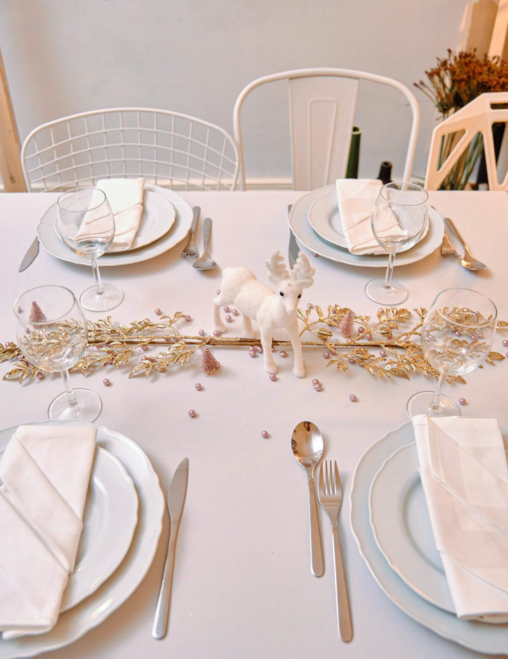 Vista de cima da mesa com pequenos pinheiros artificiais de natal para decoração, em ouro rosa com purpurinas