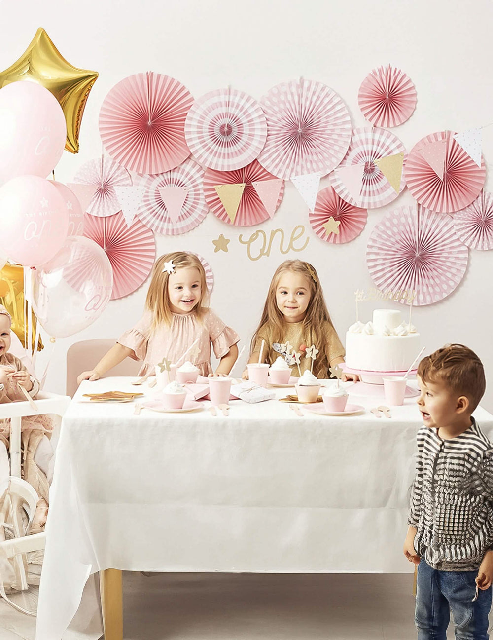 Cena de aniversário com os rosetões de papel às bolinhas e às riscas cor de rosa claro