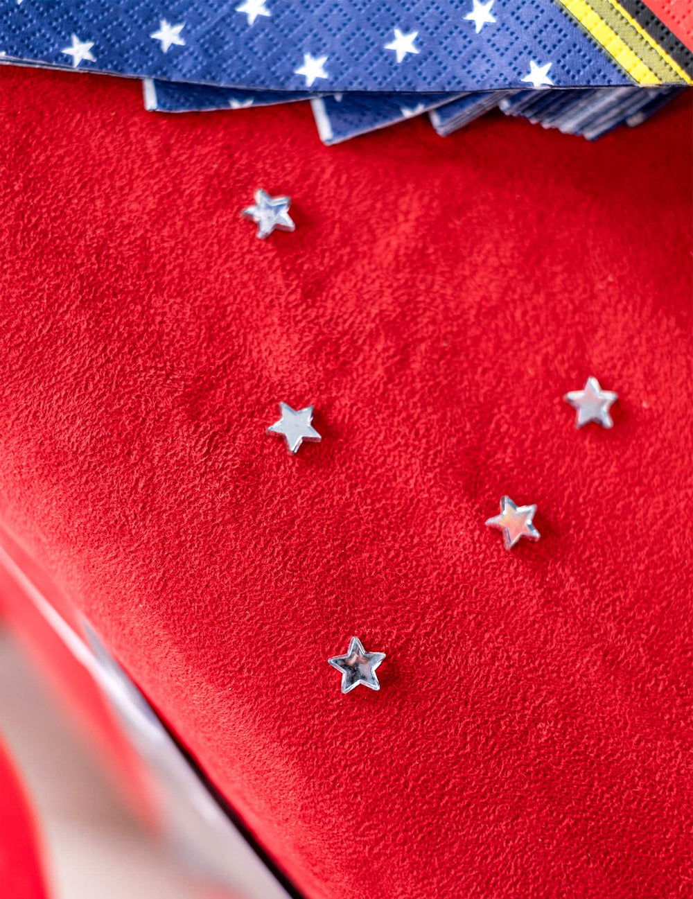 Vista de cima de estrelas espalhadas sobre fundo vermelho dos confettis de mesa estrelas espelho para festa
