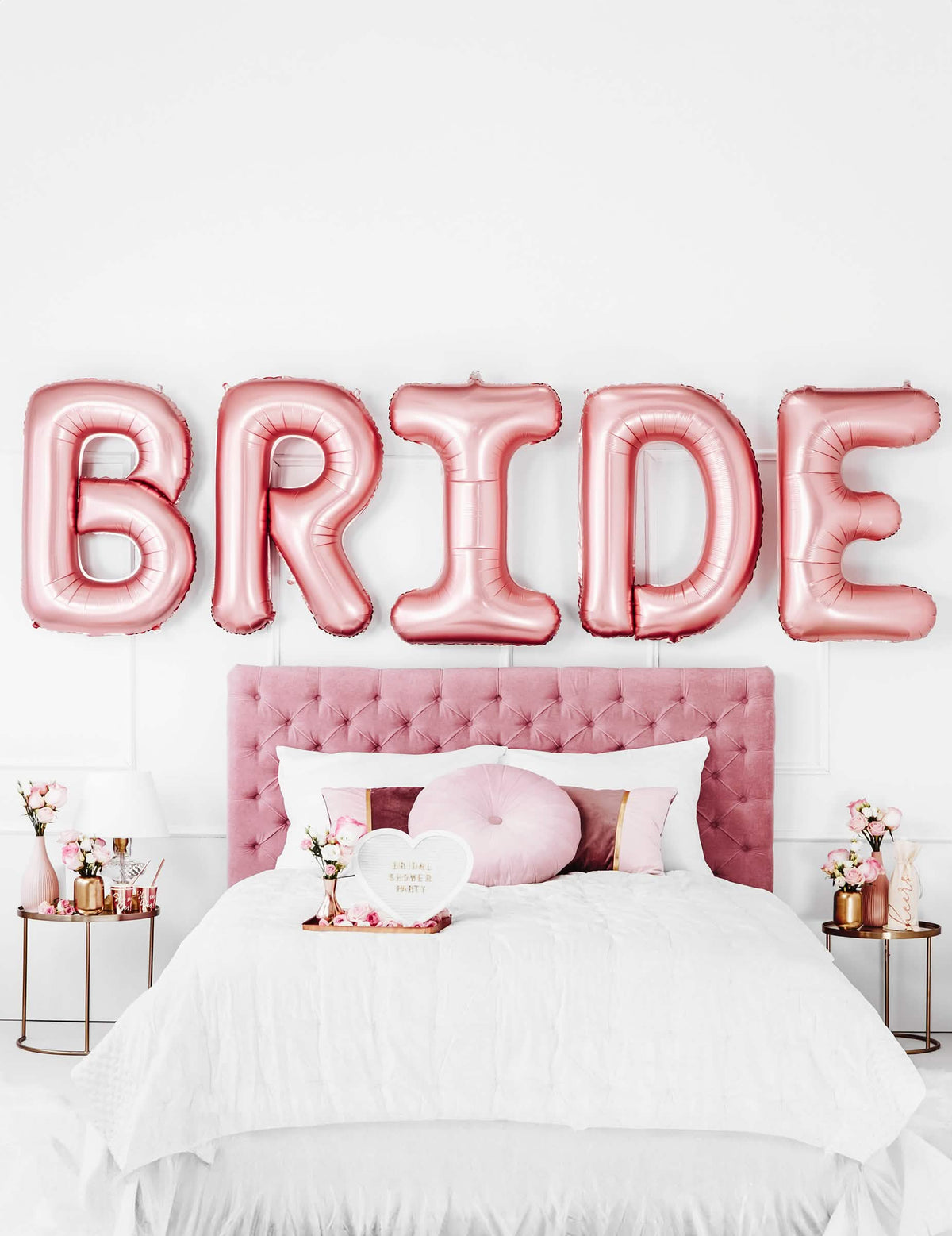Mise en scène au-dessus d'un lit des ballons lettres Bride pour EVJF rose gold
