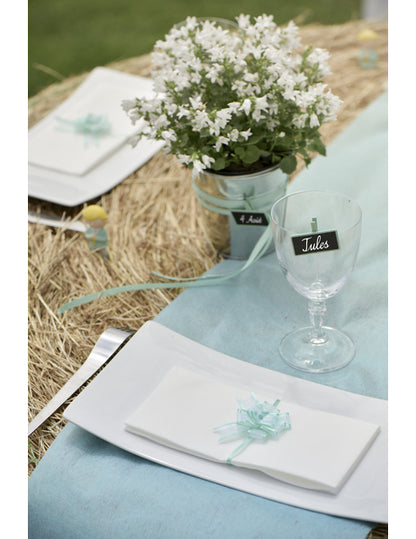 Mise en situation sur une serviette de table des minis nœuds pour décoration en organdi turquoise