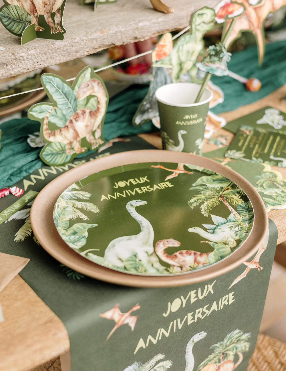 Mise en situation sur une table de fête des assiettes dinosaures joyeux anniversaire