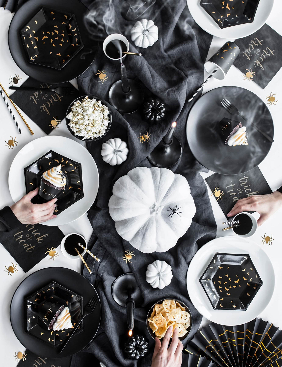 Vista de cima da decoração de mesa dos pratos de cartão hexagonais com morcegos pretos e dourados