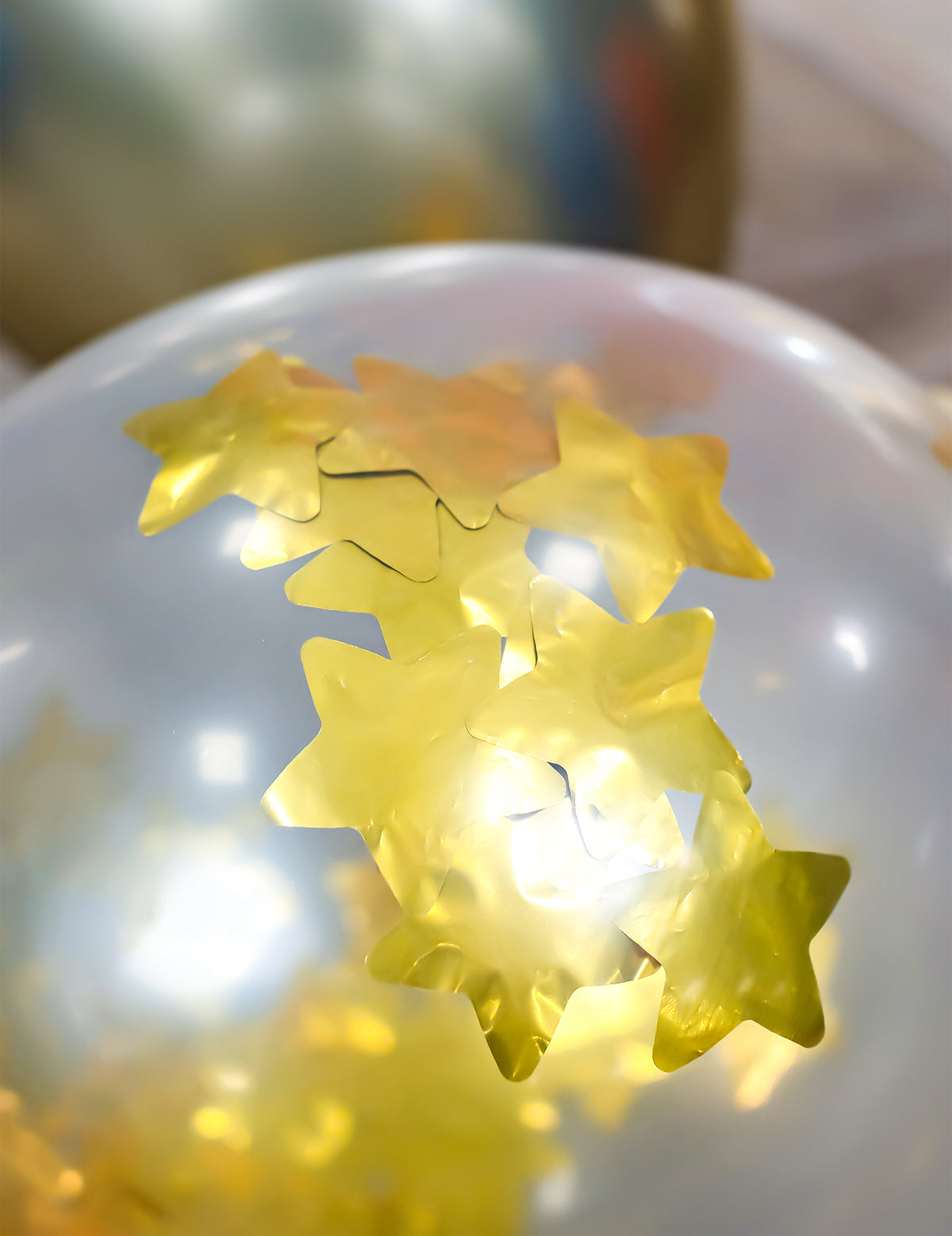 Détail des confettis étoiles du ballon en latex transparent avec étoiles dorées