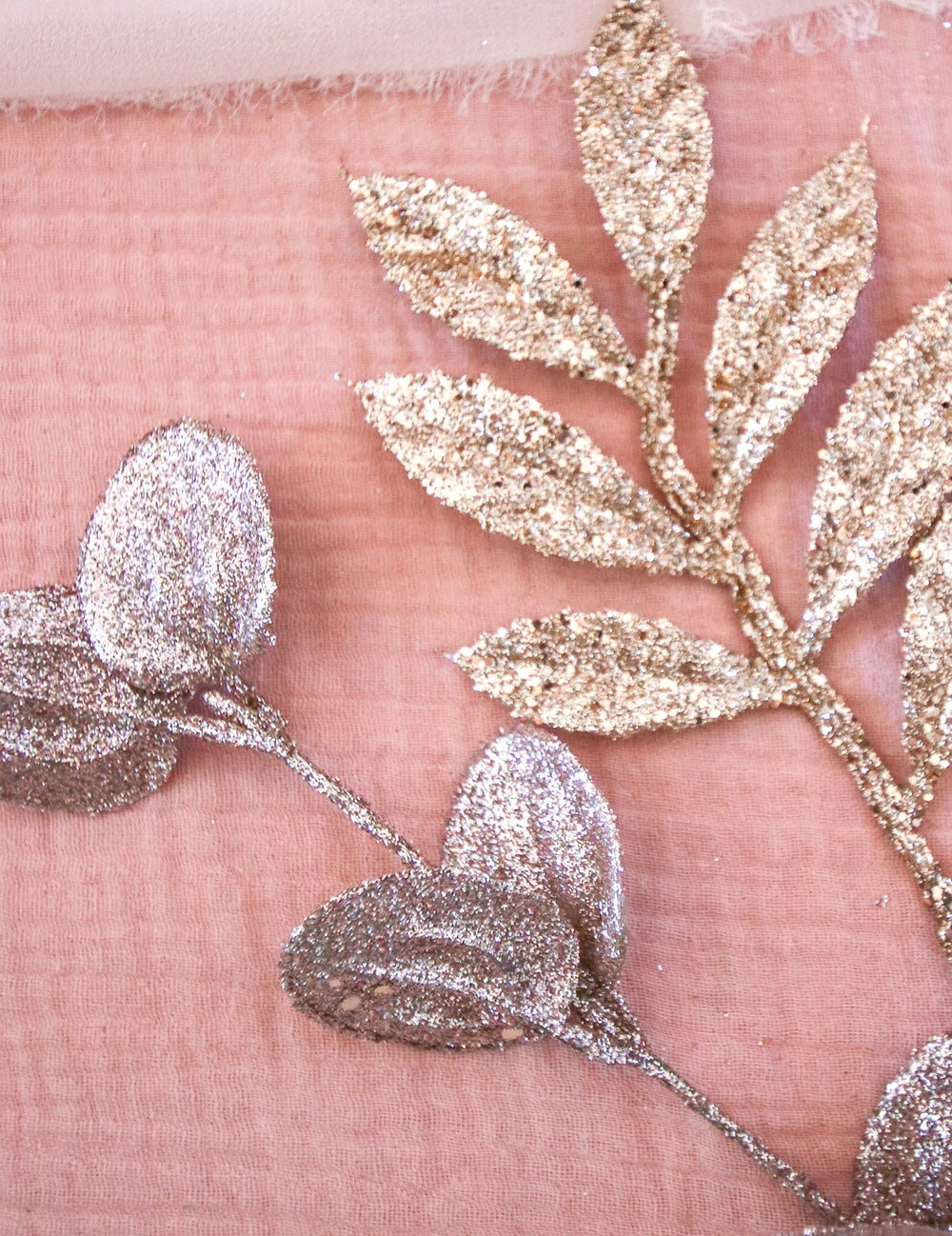 Détail du fini pailleté des branches d'eucalyptus pour décoration de fête rose gold givré à paillettes