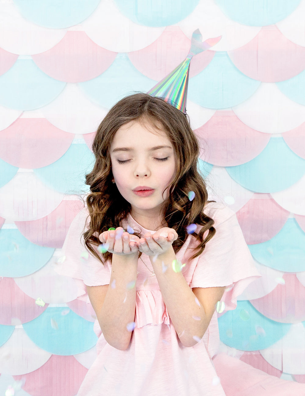 Enfant soufflant des confettis du chapeau de fête queue de sirène