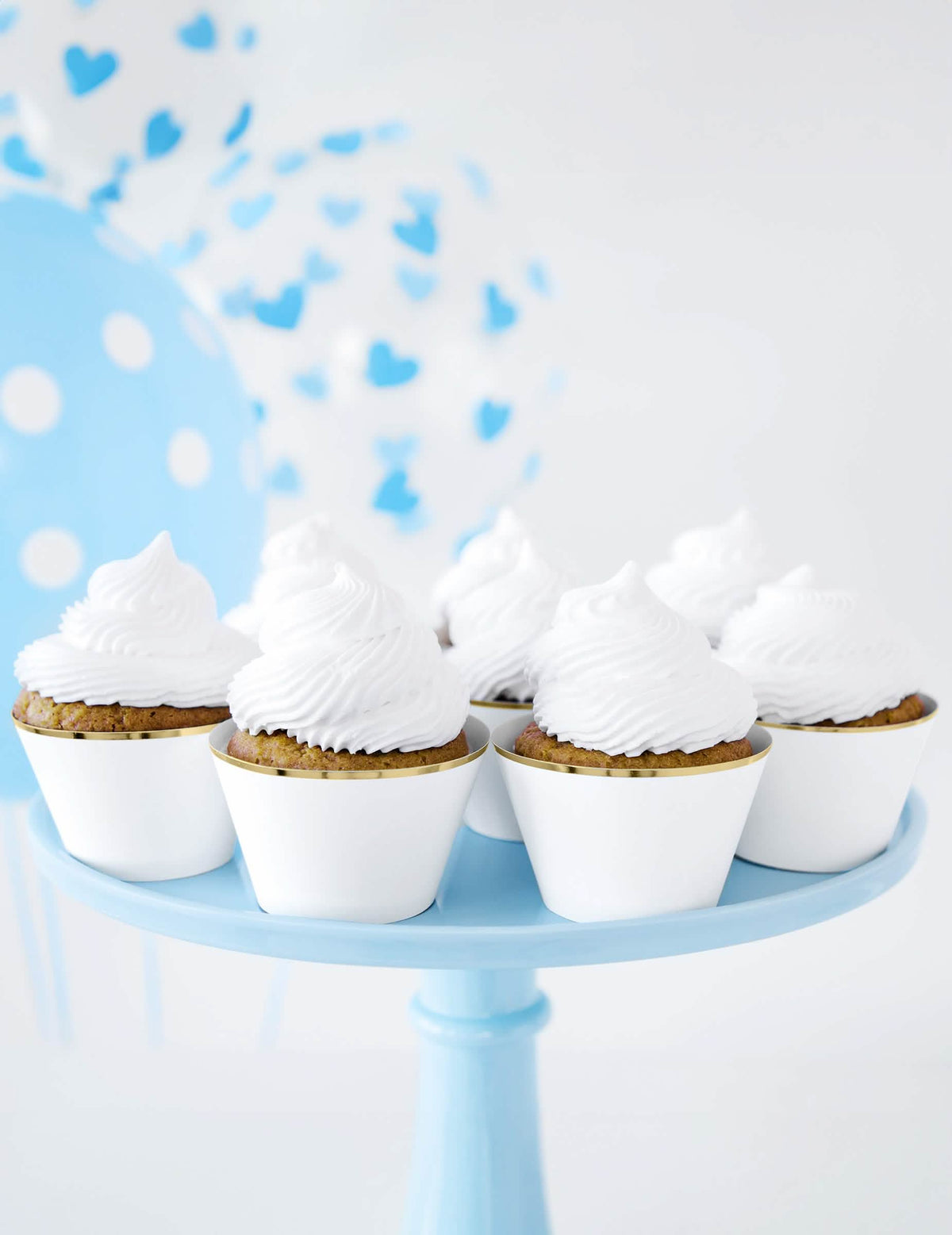 Mise en cena com balões azuis dos suportes de papel para cupcakes para casamento