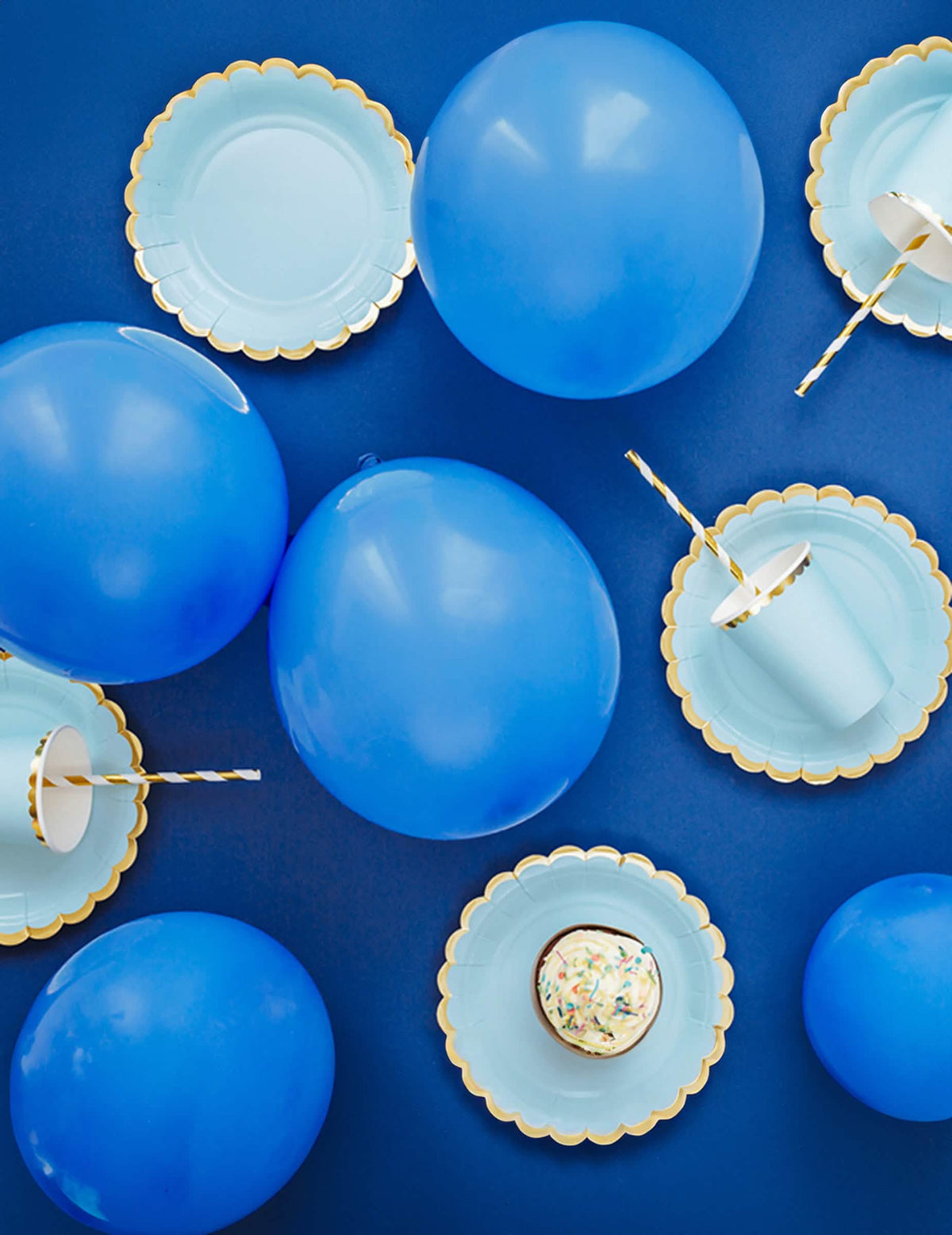 Vista de cima da decoração de festa com pratos de papel azul céu e douradura dentada