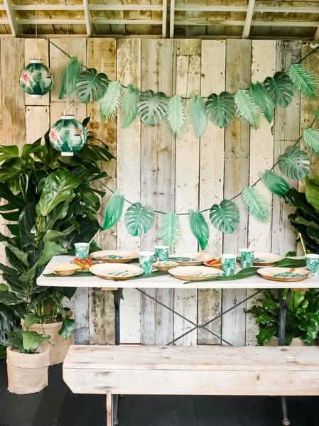 Encenação sobre uma mesa de copos de cartão tropicais verdes com motivos de folhas de palmeira