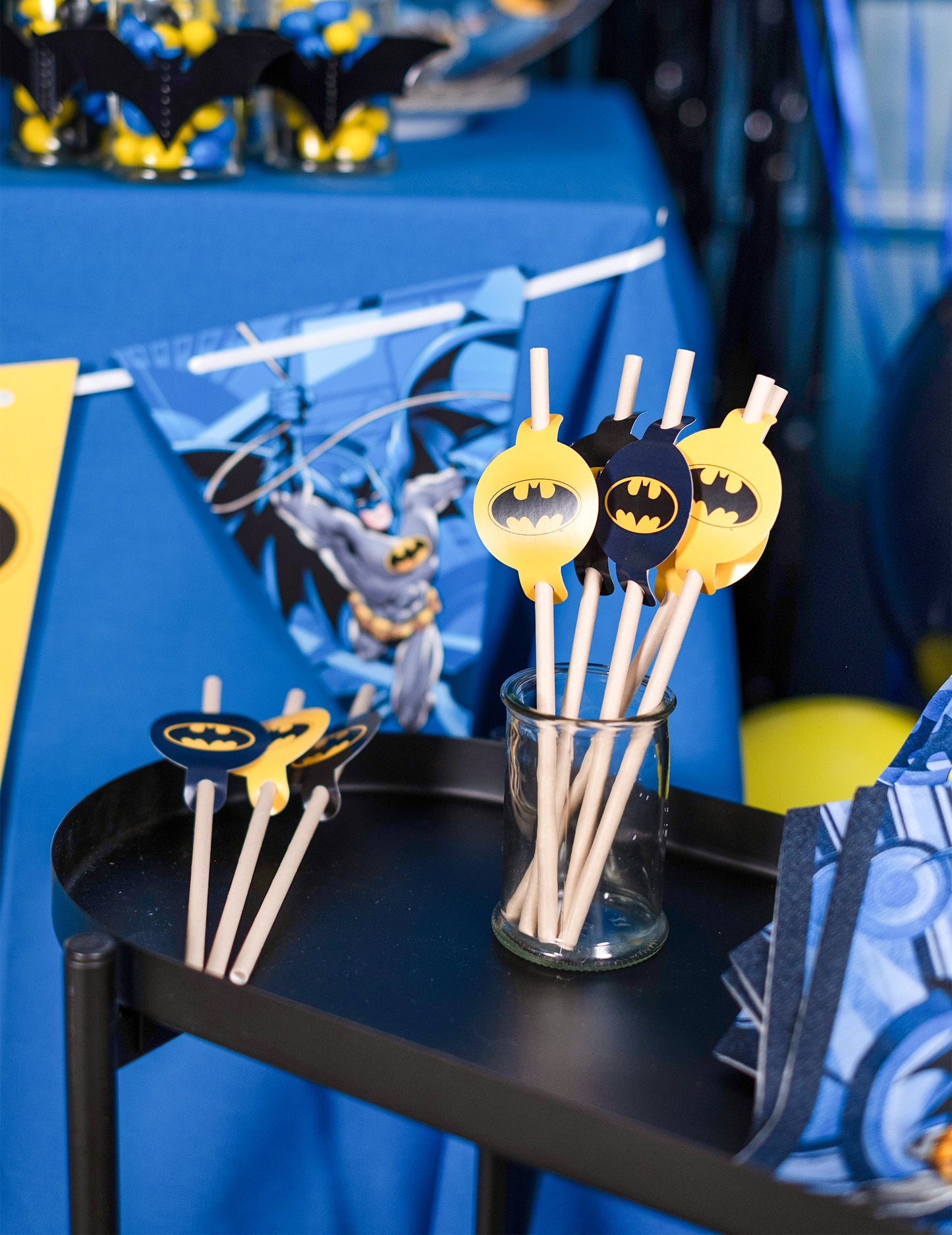Mise en scène sur un buffet d'anniversaire des pailles médaillon en carton Batman