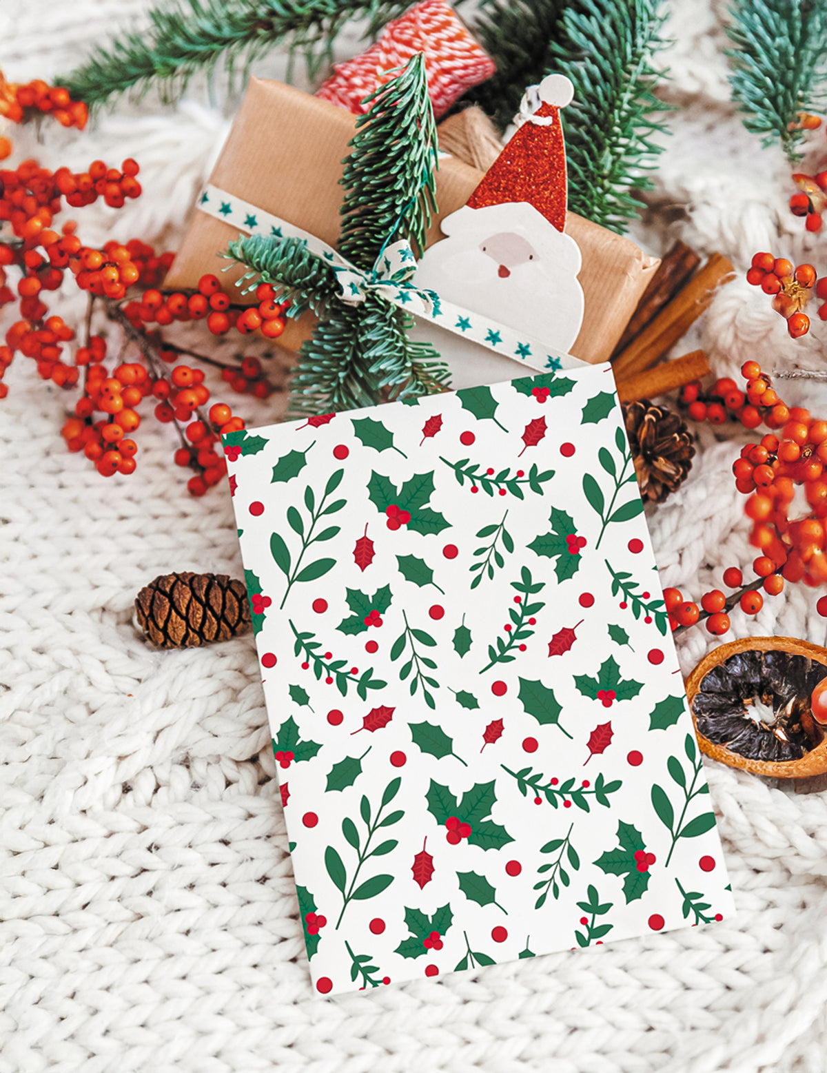 Détail des motifs de feuilles et baies de la pochette cadeau houx de Noël en papier