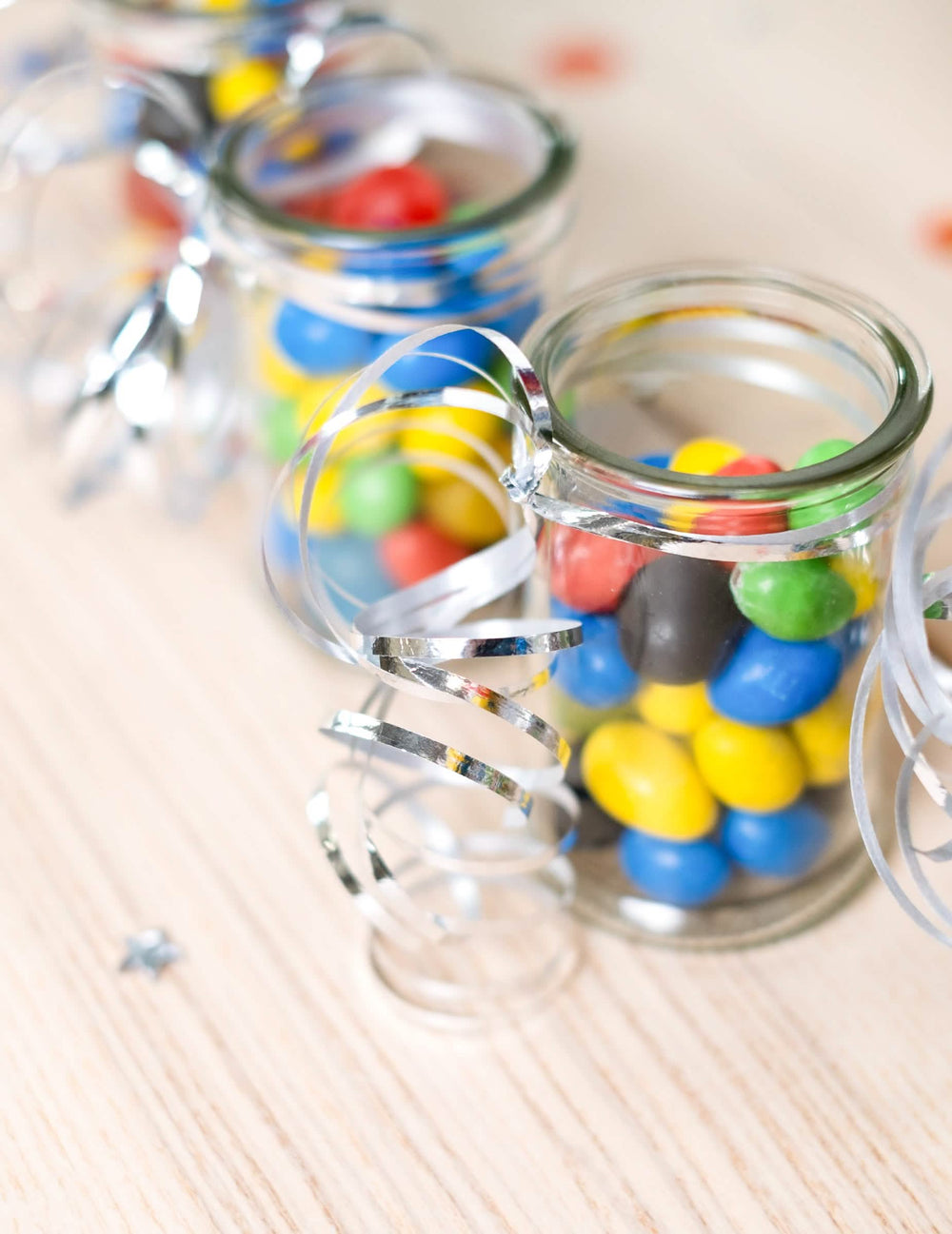 Mise em situação com pequenos frascos de rebuçados do bolduc brilhante para decoração de festa prateado