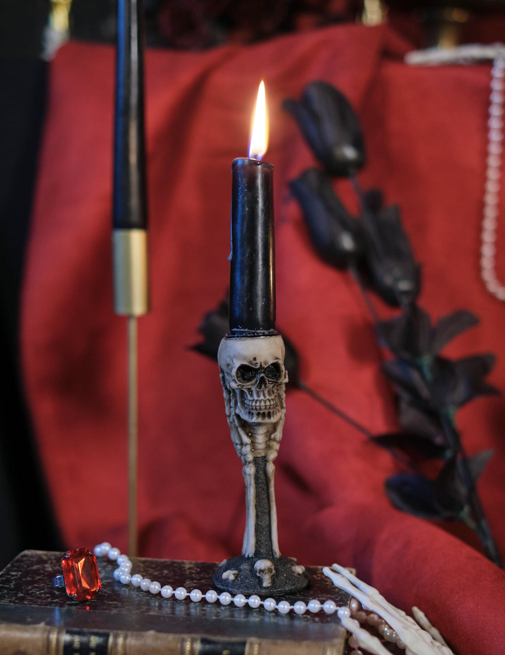 Gros plan sur la bougie noire allumée du bougeoir os et crânes