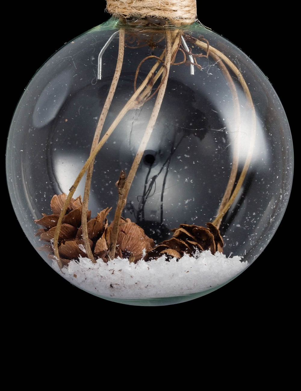 Grande plano das pinhas e da neve da bola de natal em vidro com pinhas e neve