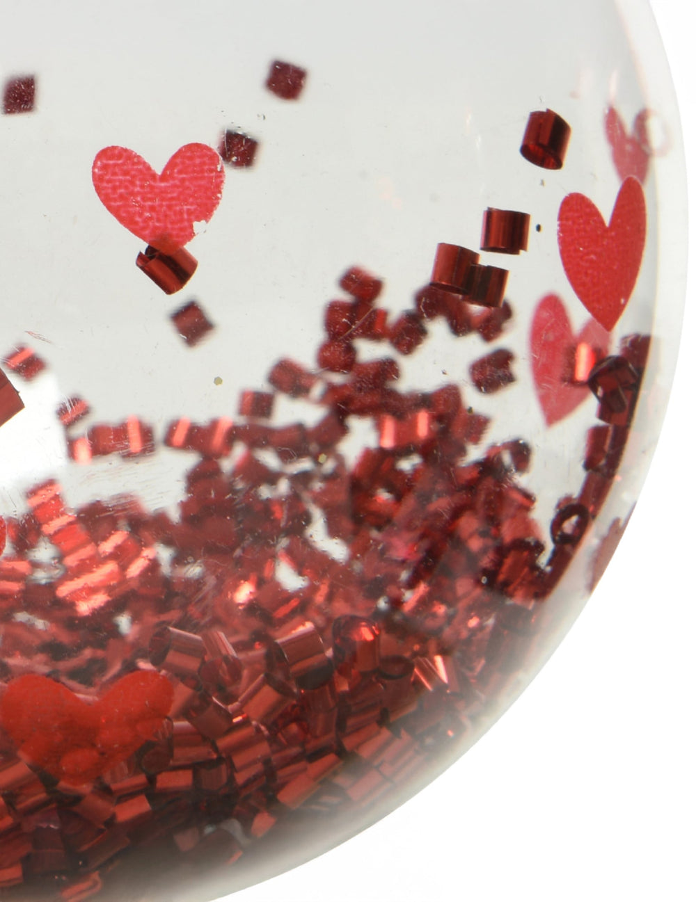Gros plan sur les confettis et motifs de la boule de noël avec cœurs rouges et confettis brillants
