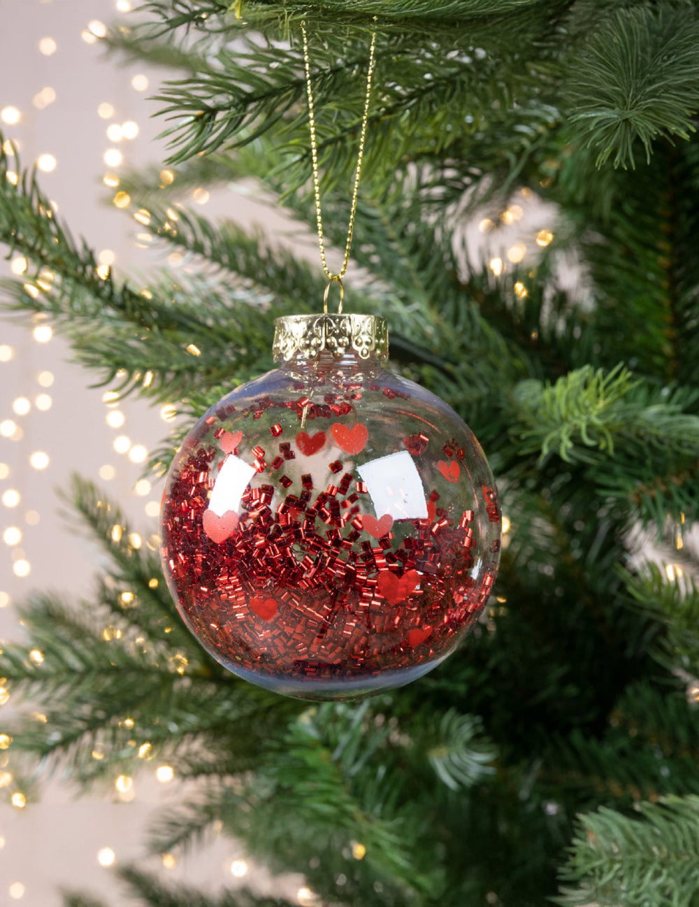 Vue suspendue dans un sapin de la boule de noël avec cœurs rouges et confettis brillants
