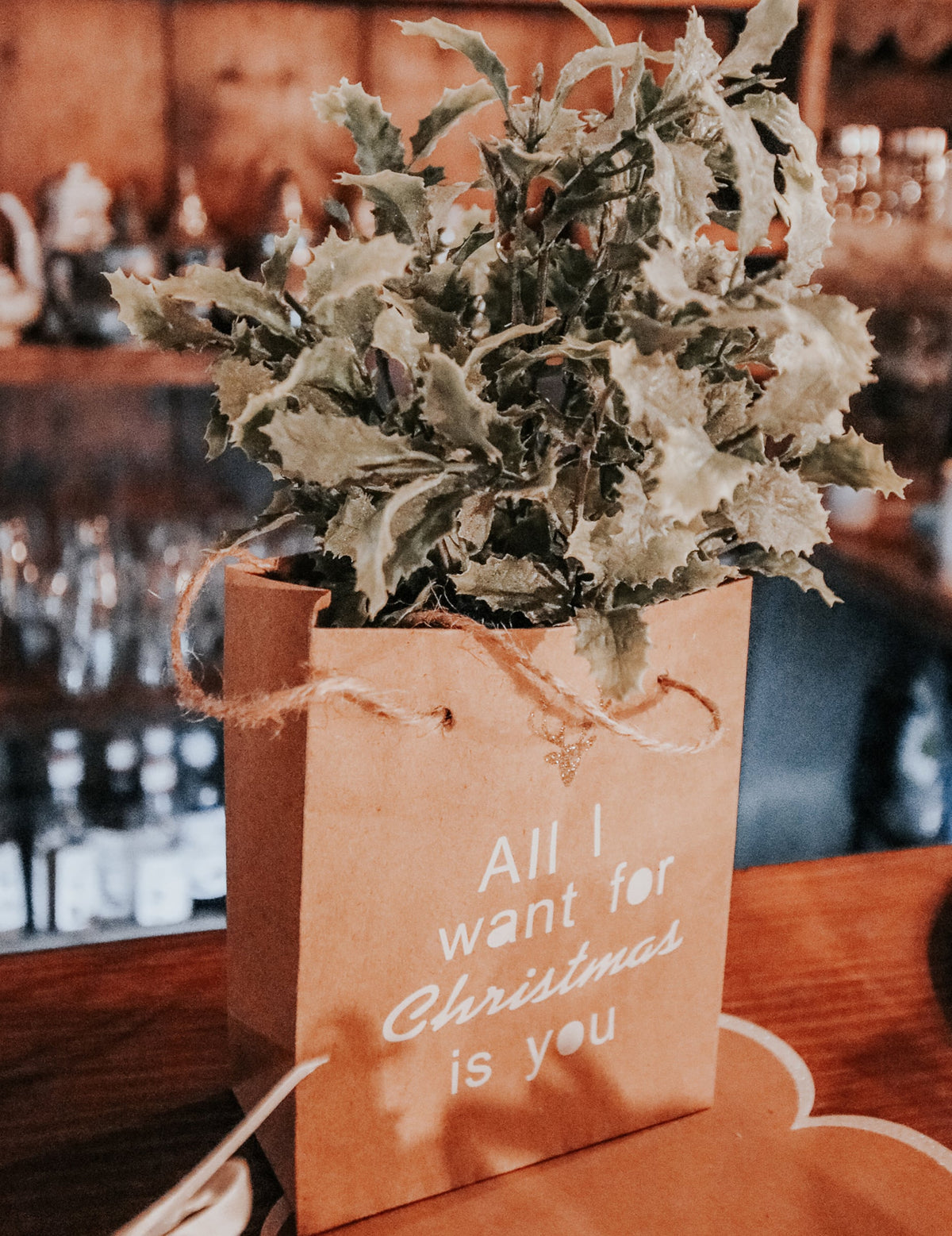 Mise en situation dans un sac cadeau kraft du bouquet de feuilles de houx pour Noël
