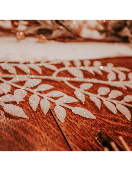 Gros plan sur les feuilles pailletées de la branche de feuillage à paillettes pour décoration blanche
