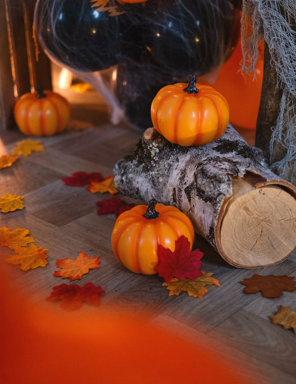 Mise en scène avec bûche et feuilles d'automne de la citrouille en résine d'Halloween