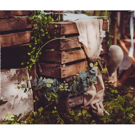 Mise em situação sobre caixas de madeira da coroa em metal de eucalipto e flores brancas círculo dourado