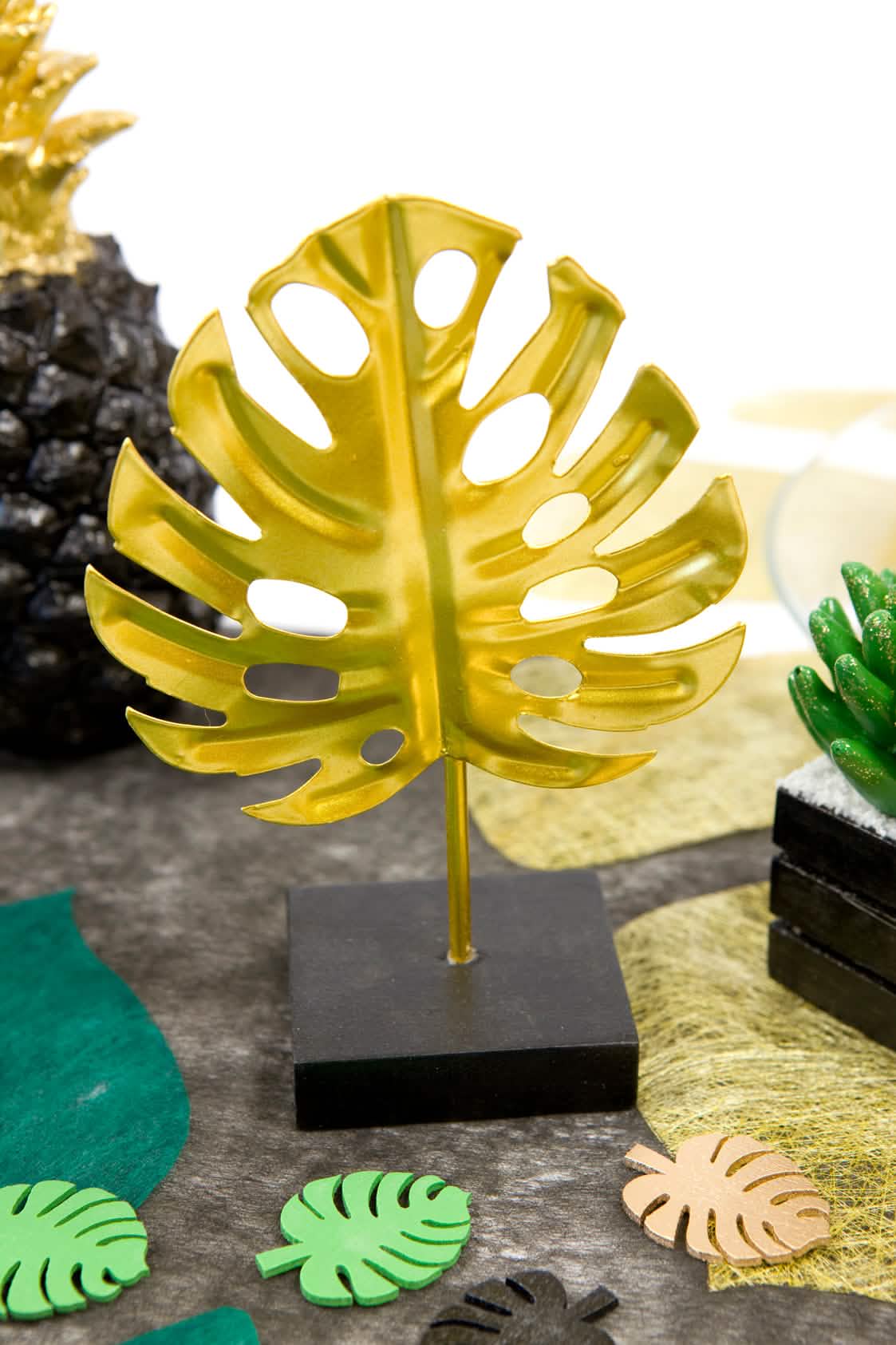 Decoração em metal sobre base de folha tropical em contexto de apresentação