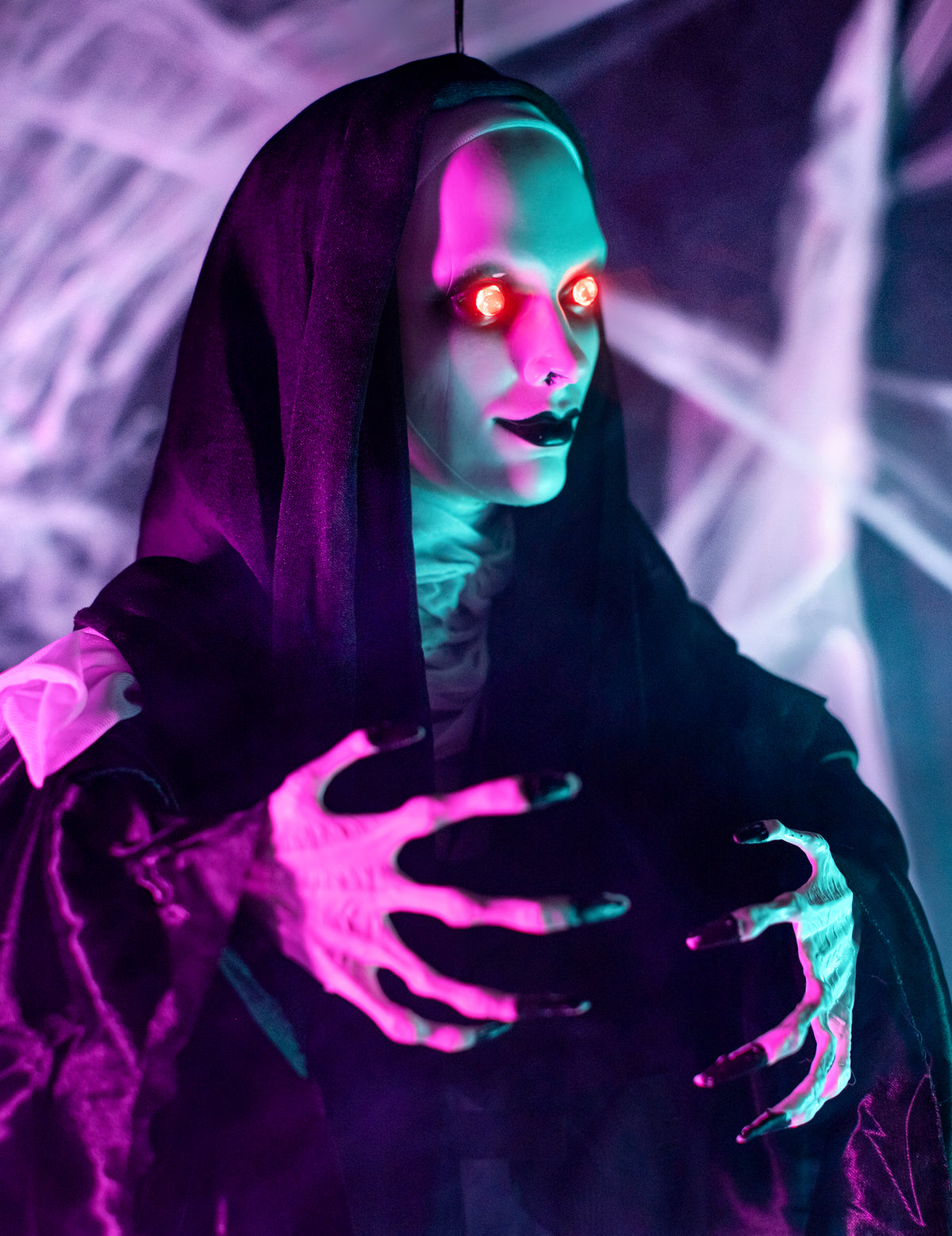 Gros plan sur le visage aux yeux rouges et les mains de la décoration lumineuse nonne suspendue