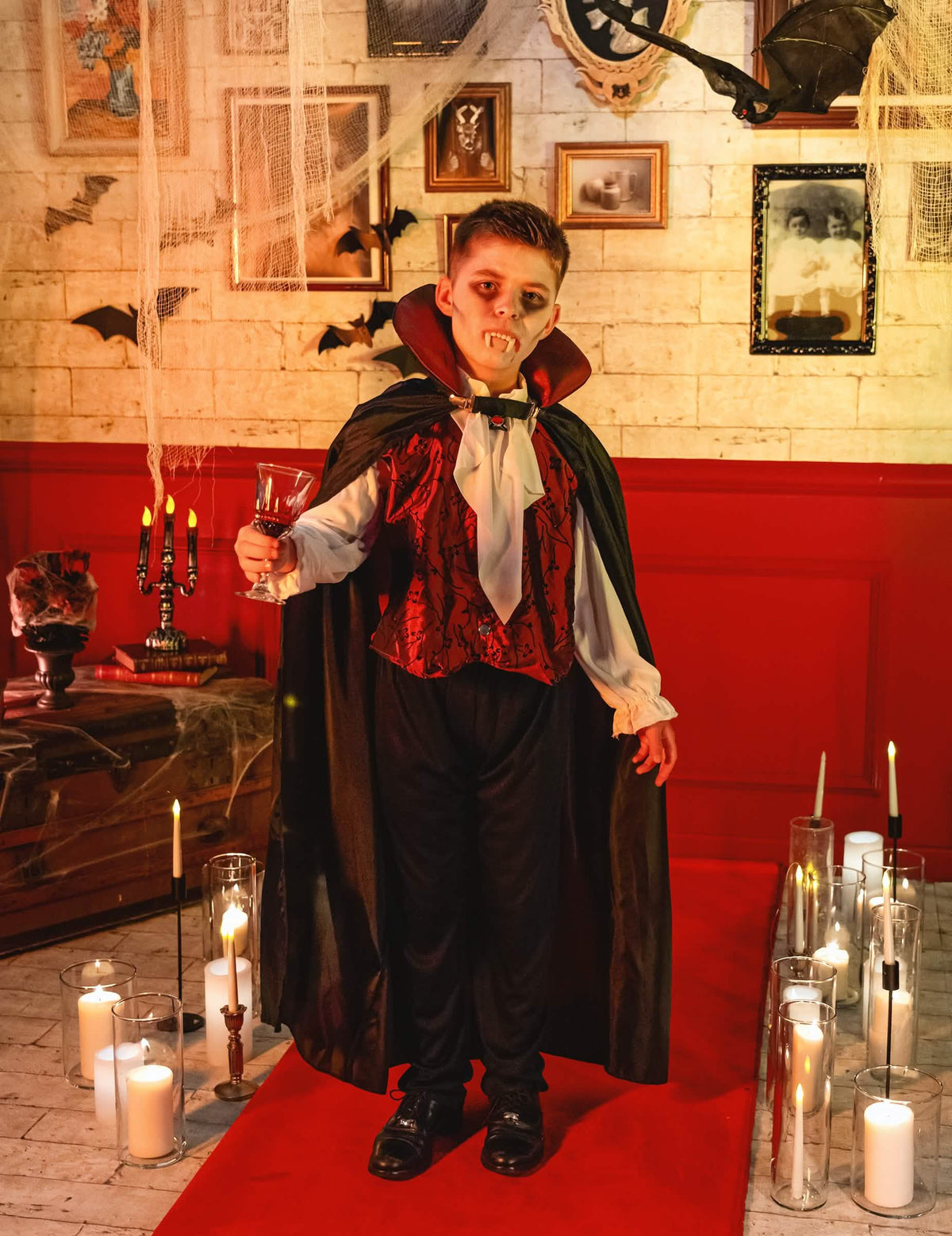Mise en situação do disfarce de vampiro elegante para menino num cenário de halloween com velas