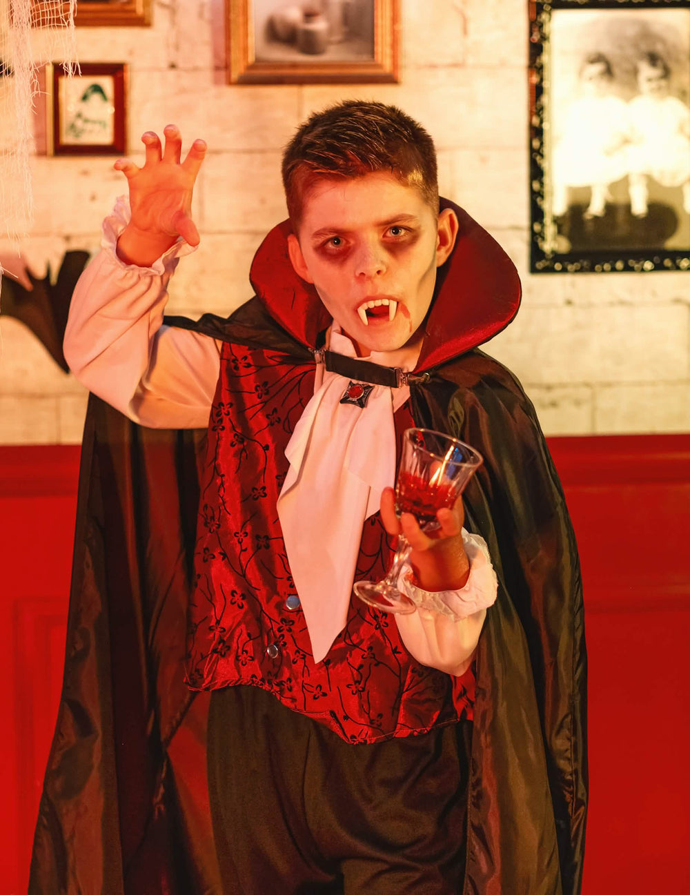 Mise em situação com dentes de vampiro e copo do disfarce de vampiro elegante para menino